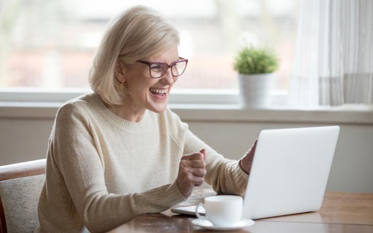 Personne retraitée enthousiaste devant un ordinateur