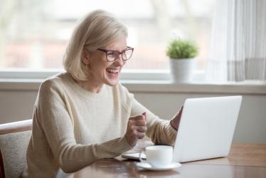 Personne retraitée enthousiaste devant un ordinateur